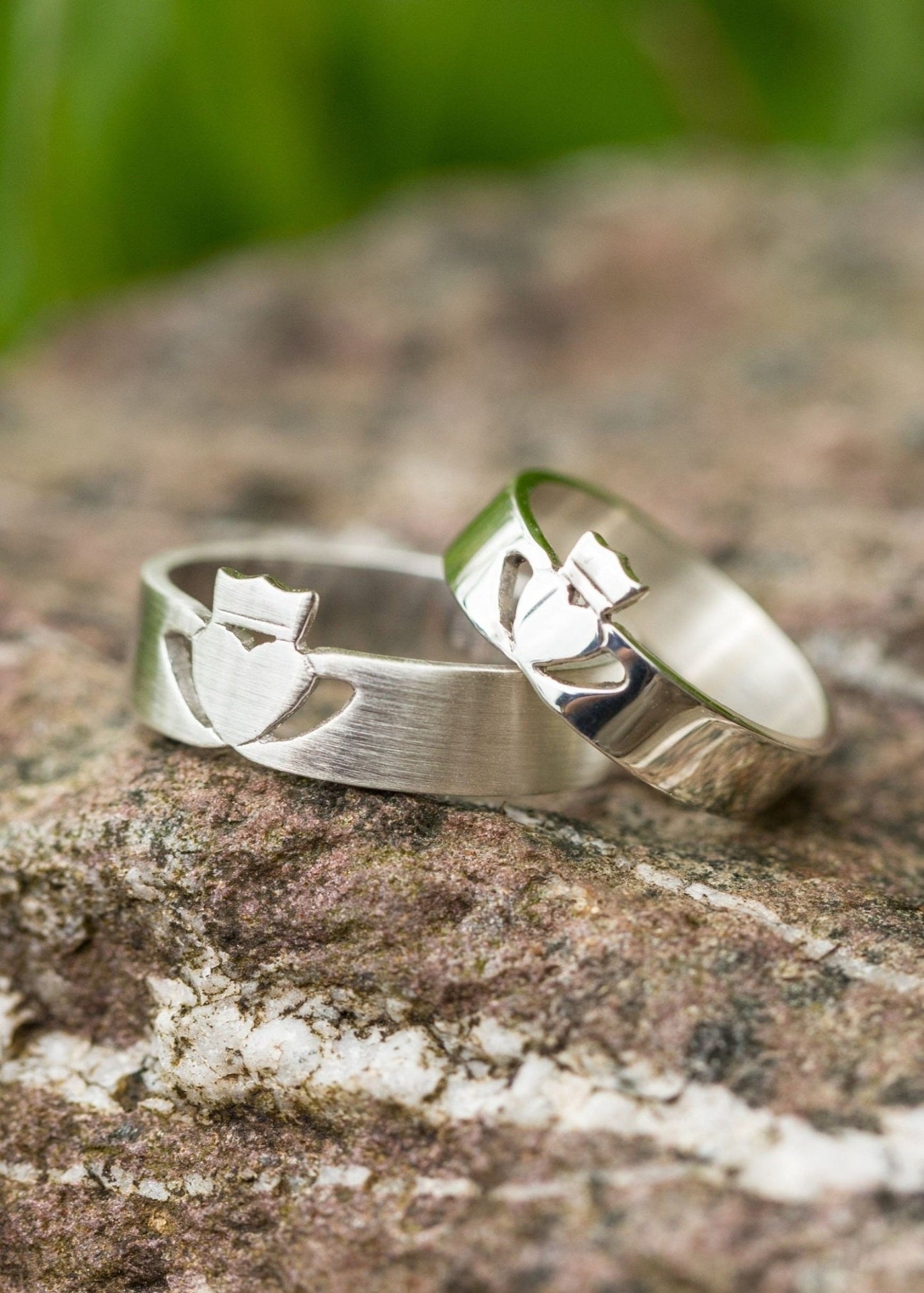 White Gold Claddagh wedding rings set in a modern style displayed on a rock