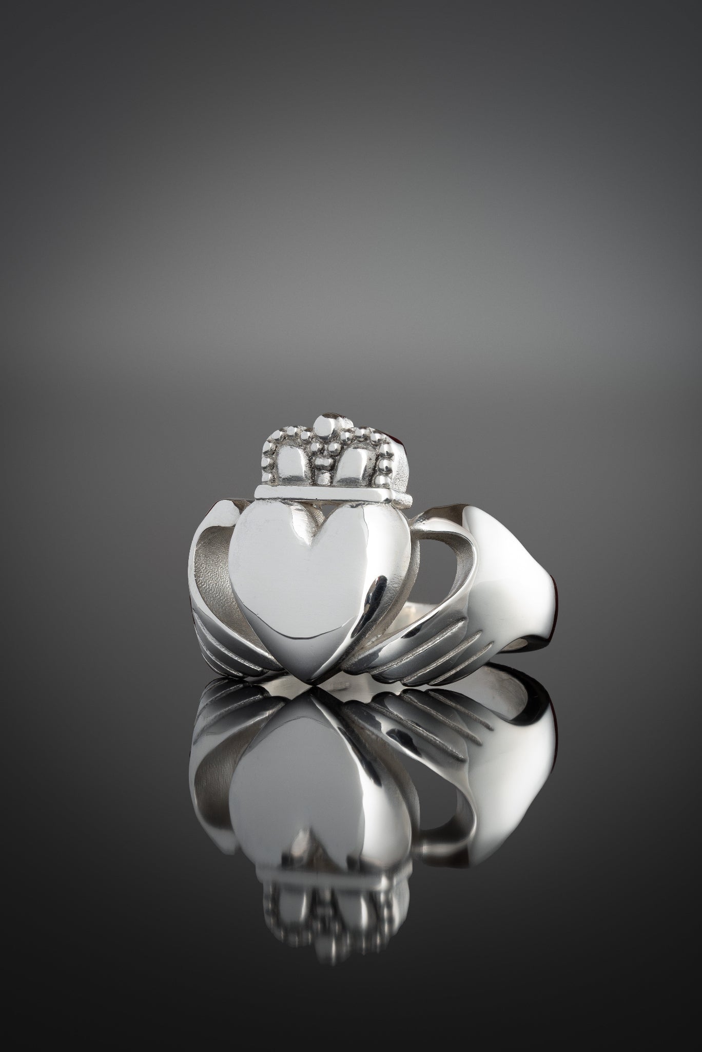 extra large chunky claddagh ring from the side on a black background