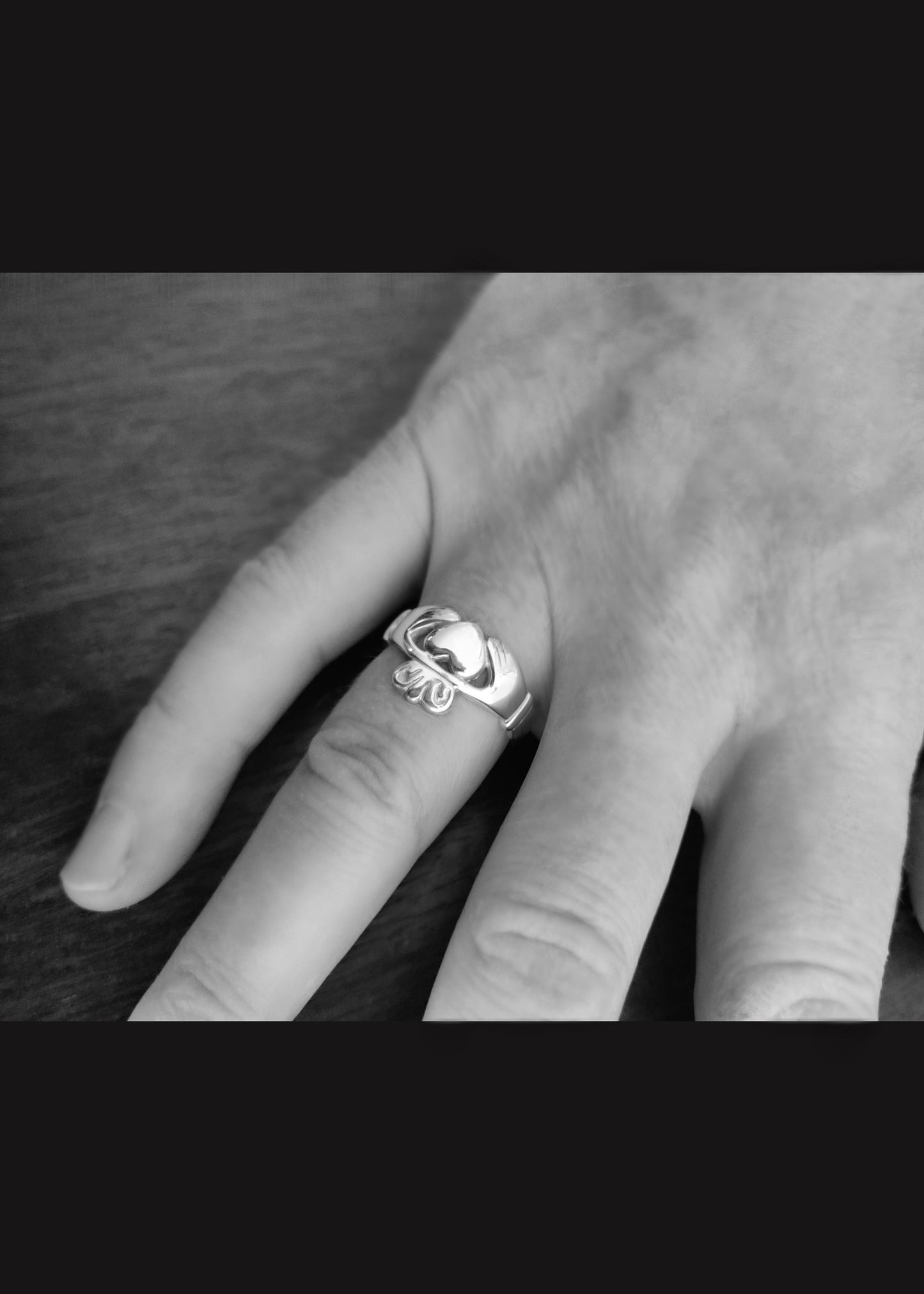 The image shows a men's claddagh ring in silver on a man's hand