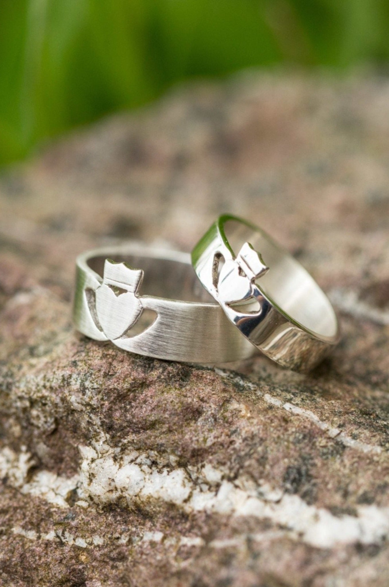 His and hers modern Claddagh ring displayed on a rock