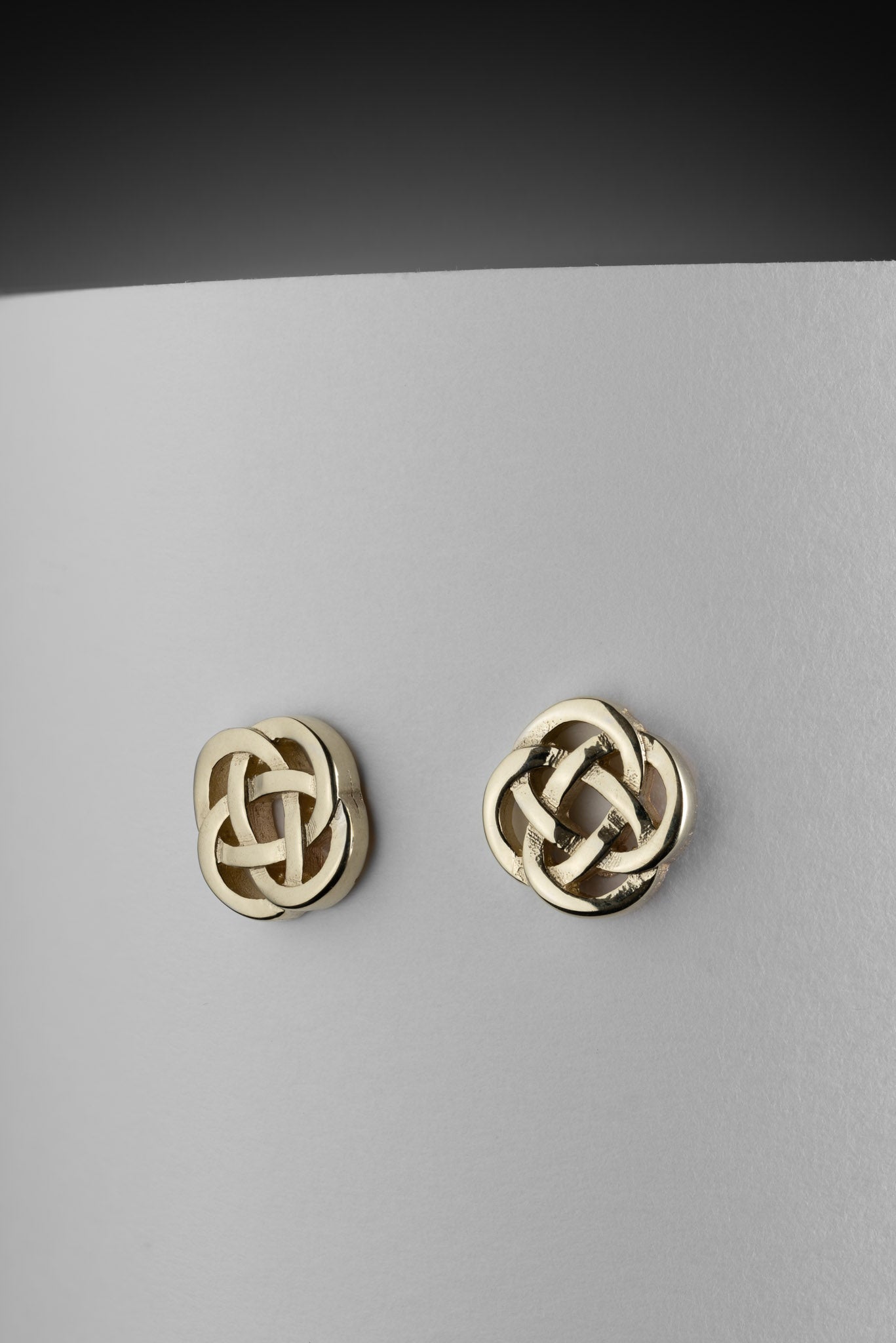 gold celtic knot earrings on white background