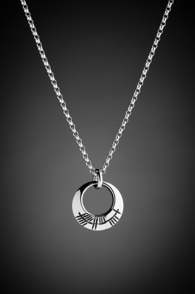Silver pendant engraved with the Irish word A stor in Ogham writing